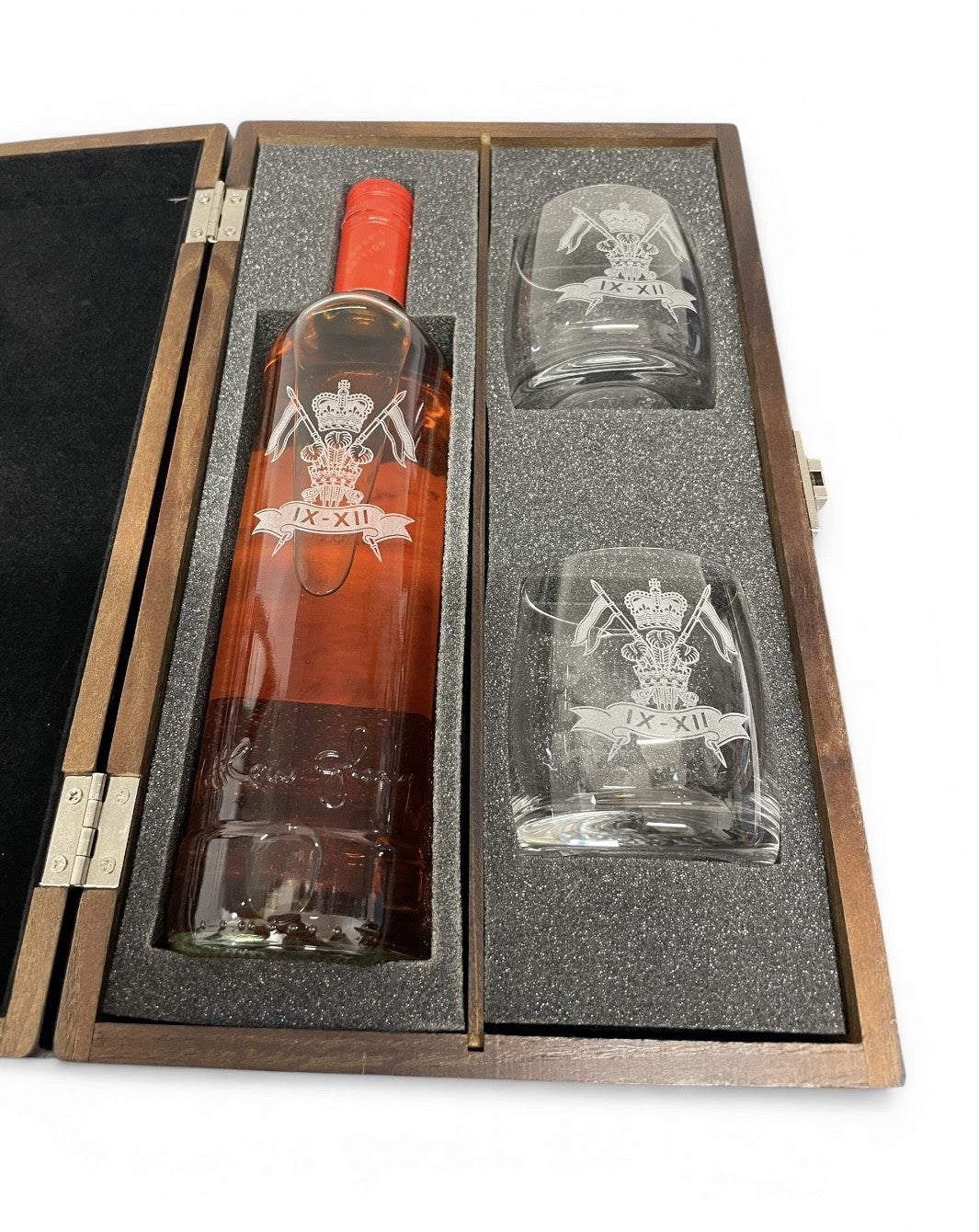 Bottle of whisky and two glasses in a wooden case with engraved design.